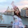 woman in venetian clothes and mask on bridge in venice
