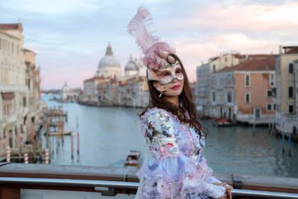 woman in venetian clothes and mask on bridge in venice