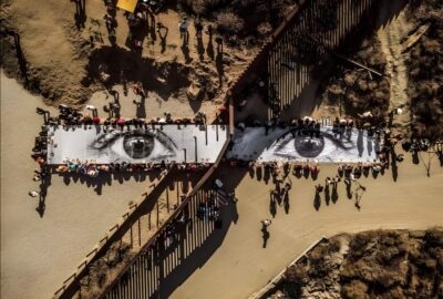 JR (French, born 1983). Migrants, Mayra, Picnic across the Border, Tecate, Mexico—U.S.A., 2017. Installation image. Wheat-pasted poster on table. © JR-ART.NET