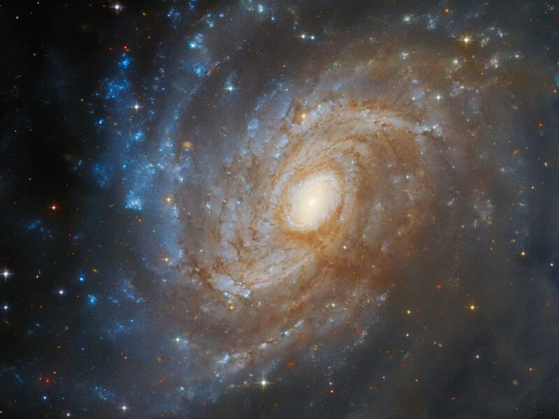 The Stunning Spiral: Hubble Captures the Intricate Beauty of Galaxy IC 4633, Hidden Within a Sea of Dust