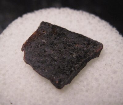 An angrite meteorite specimen — the rare type of ancient volcanic rock linking to a Moon-sized protoplanet from the early solar system
