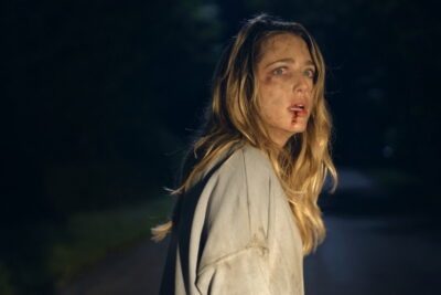 Jessica Rothe as Ellie, bloodied and disoriented on a dark road at night, in BT Meza's horror film Affection.