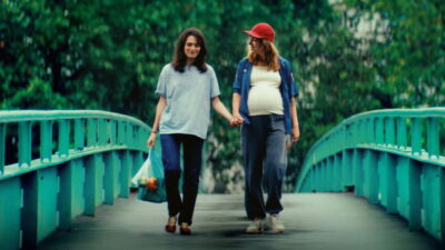 Céline (Ella Rumpf) and a pregnant Nadia (Monia Chokri) hold hands on a footbridge in Alice Douard's Love Letters.