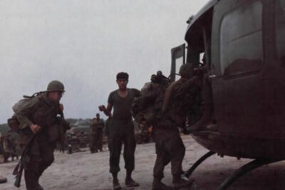 U.S. soldiers loaded with packs and rifles board a UH-1 Huey helicopter on a muddy airstrip in Vietnam