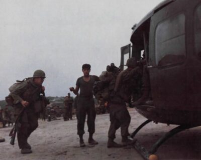 U.S. soldiers loaded with packs and rifles board a UH-1 Huey helicopter on a muddy airstrip in Vietnam