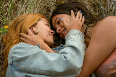Coley and Sonya lie close together in a sunlit field in Hayley Kiyoko's feature debut Girls Like Girls