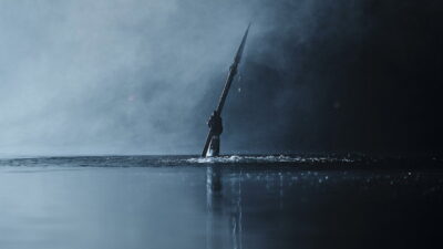 A hand rises from the misted lake of Camp Miasma clutching a blade in Jane Schoenbrun's slasher Teenage Sex and Death at Camp Miasma.