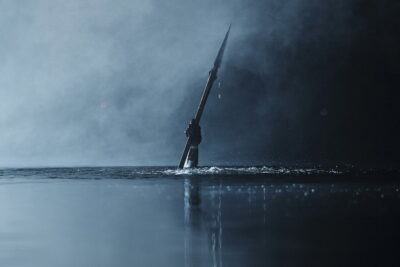 A hand rises from the misted lake of Camp Miasma clutching a blade in Jane Schoenbrun's slasher Teenage Sex and Death at Camp Miasma.