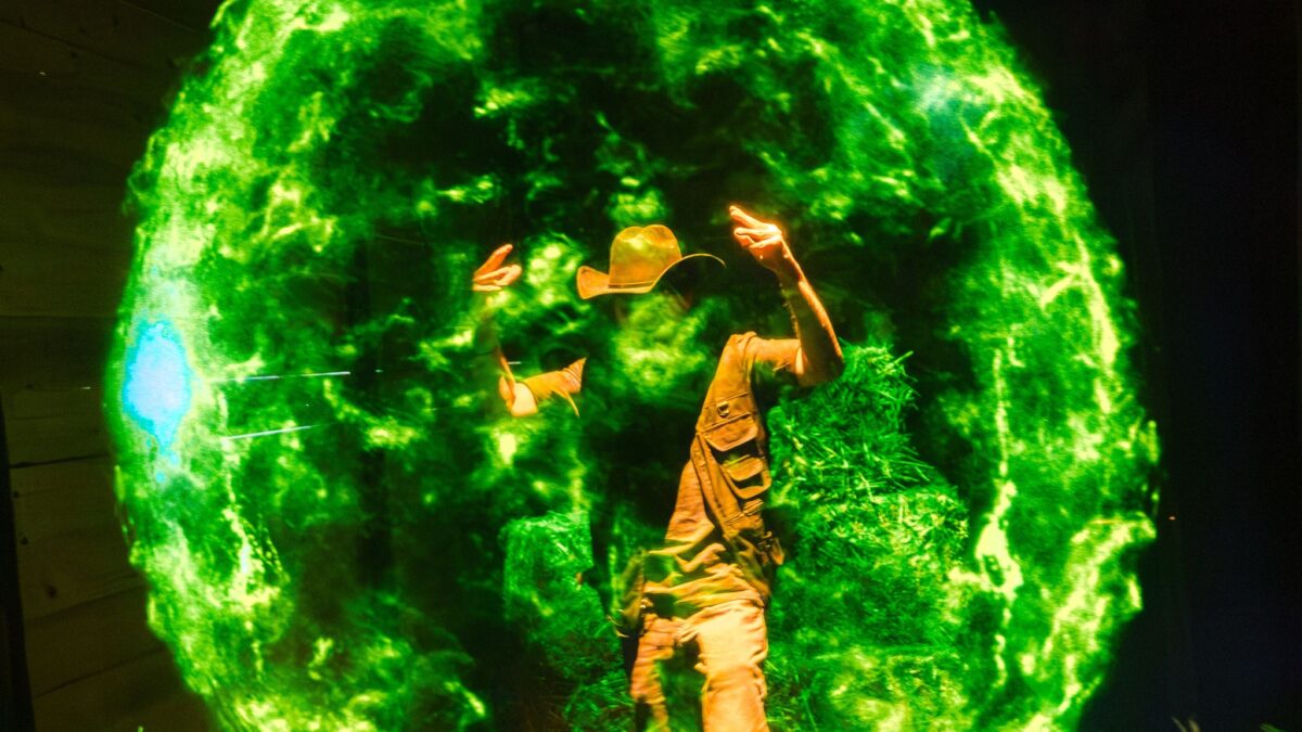 A visitor lit by a green energy sphere inside the Lanterns activation at Comic-Con