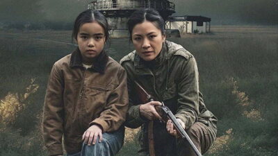 Constance Wu holds a rifle beside a frightened child in an open field in William Woods’s science-fiction thriller The Outer Threat