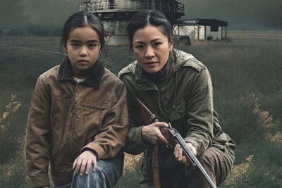 Constance Wu holds a rifle beside a frightened child in an open field in William Woods’s science-fiction thriller The Outer Threat