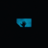 Silhouetted hand reaching toward a glowing blue screen in darkness — parasocial bonds in the digital age