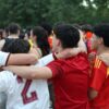 Spain national football team supporters in red jerseys with their arms around each other