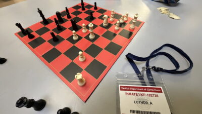 Chessboard and a VanKull Department of Corrections inmate badge for Luthor, A, in a promotional image for Man of Tomorrow