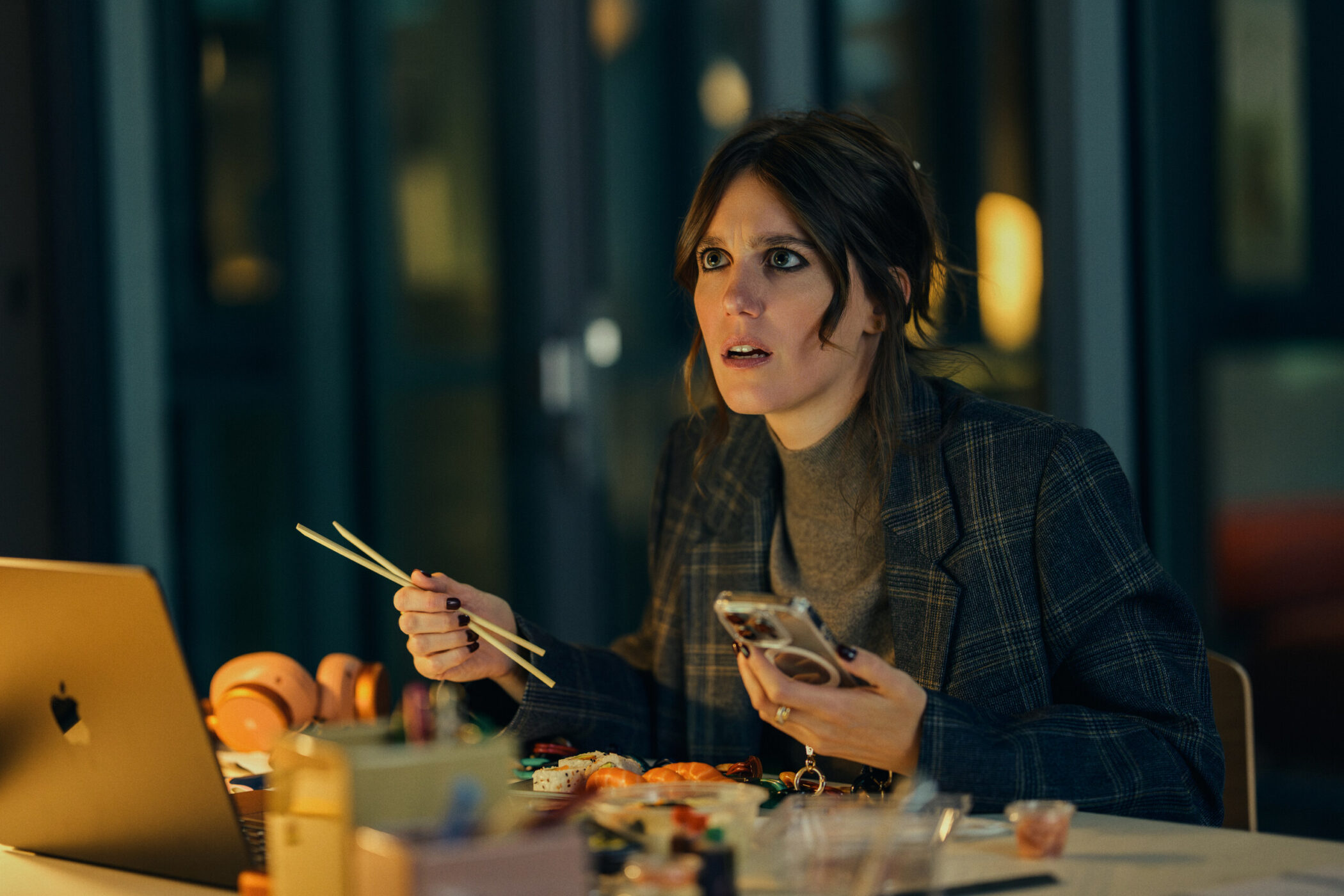 An agent eating sushi at her desk, staring at a laptop, in Call My Agent! The Movie