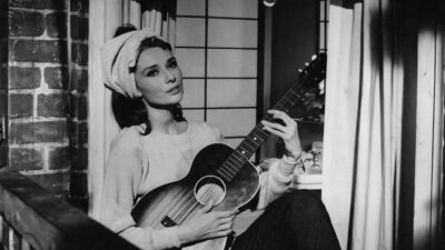 Audrey Hepburn sitting on the fire escape with a guitar in Breakfast at Tiffany's, 1961