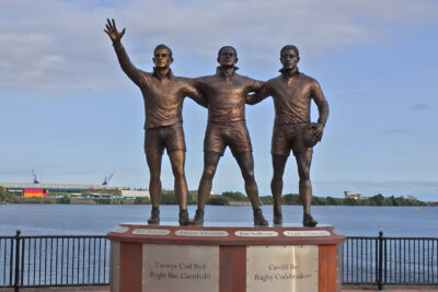 Monumento Rugby Codebreakers en Cardiff Bay, con las figuras de Guy Risman, Billy Boston y Clive Sullivan