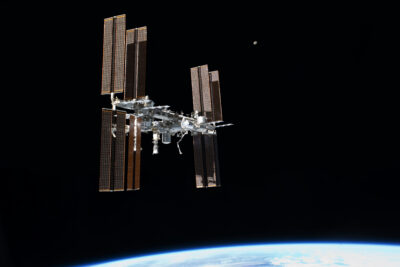The International Space Station photographed in orbit with Earth atmosphere visible below