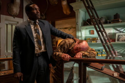 Special Agent Wayne Strider (Yahya Abdul-Mateen II) stands over a suspect in a Delta gun shop in Elegance Bratton's By Any Means (2026).
