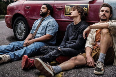 The three leads of Macon Blair's Idiots slumped against a battered van in a production still