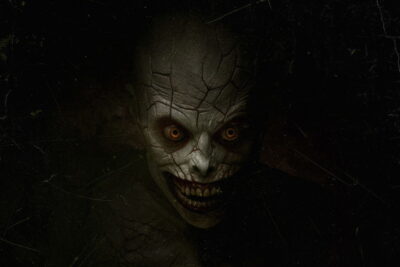 A cracked, hollow-eyed demon glares from the dark in Jeremiah Kipp's horror film The Mortuary Assistant.