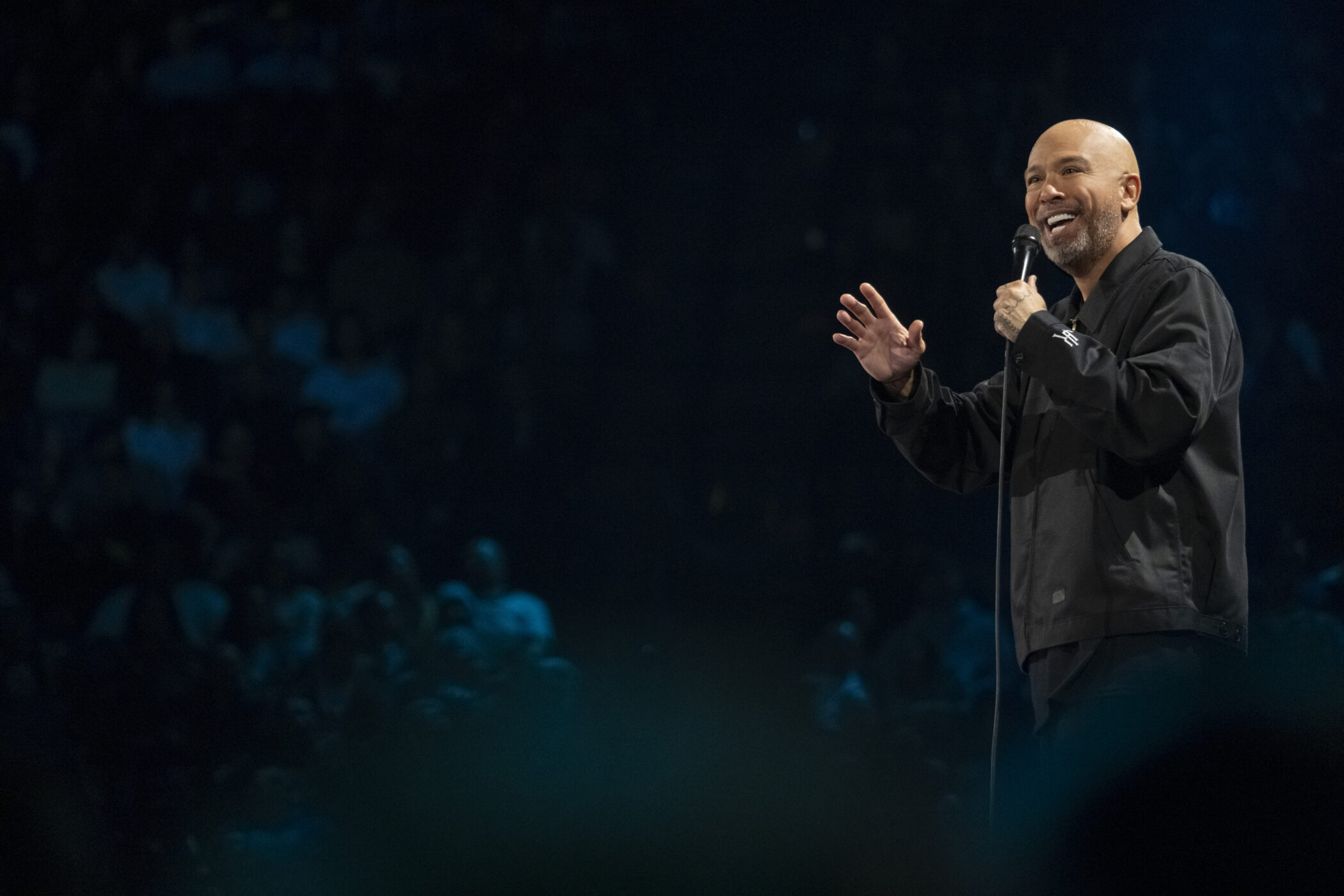 Jo Koy on stage with a microphone before the crowd at The Adventist Health Arena in Stockton in Blue in the Face