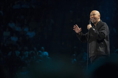 Jo Koy on stage with a microphone before the crowd at The Adventist Health Arena in Stockton in Blue in the Face