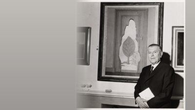 Rene Magritte photographed in 1961 beside one of his paintings