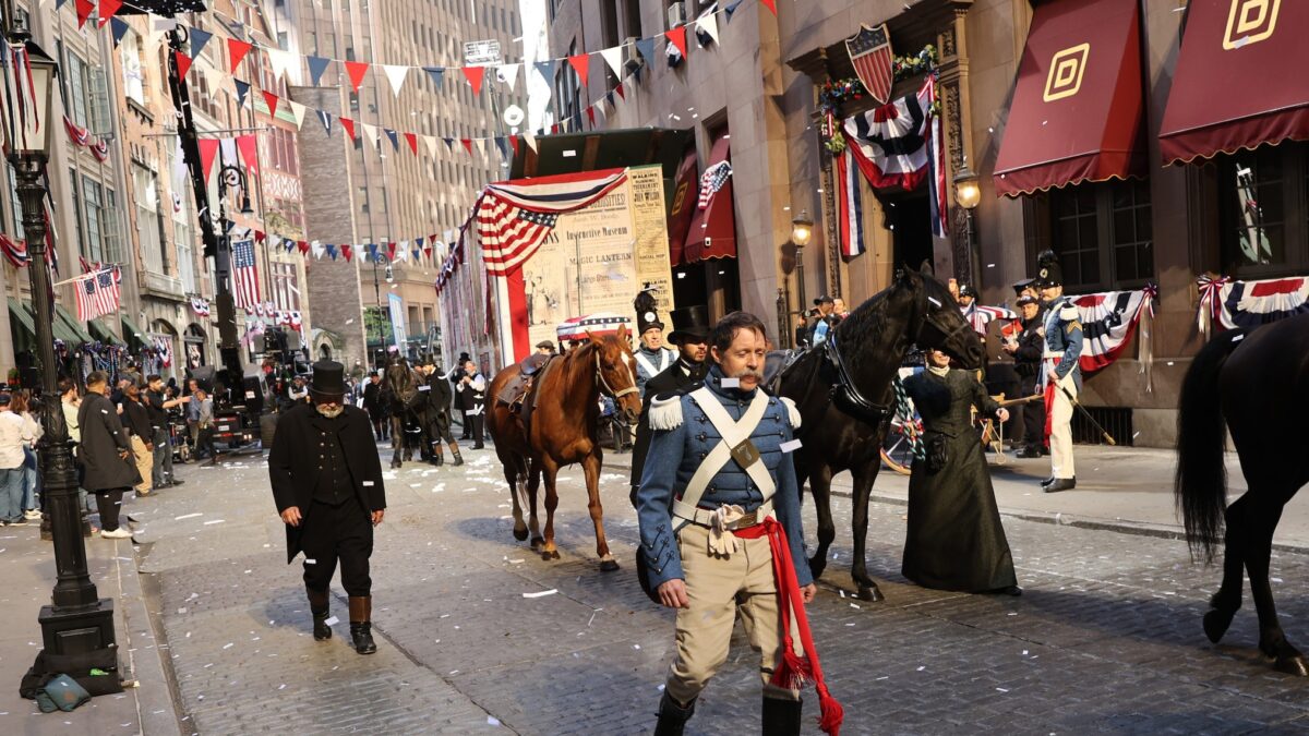 Extras in Revolutionary War-era uniforms during filming of The Gilded Age Season 4 parade sequence on South William Street in New York