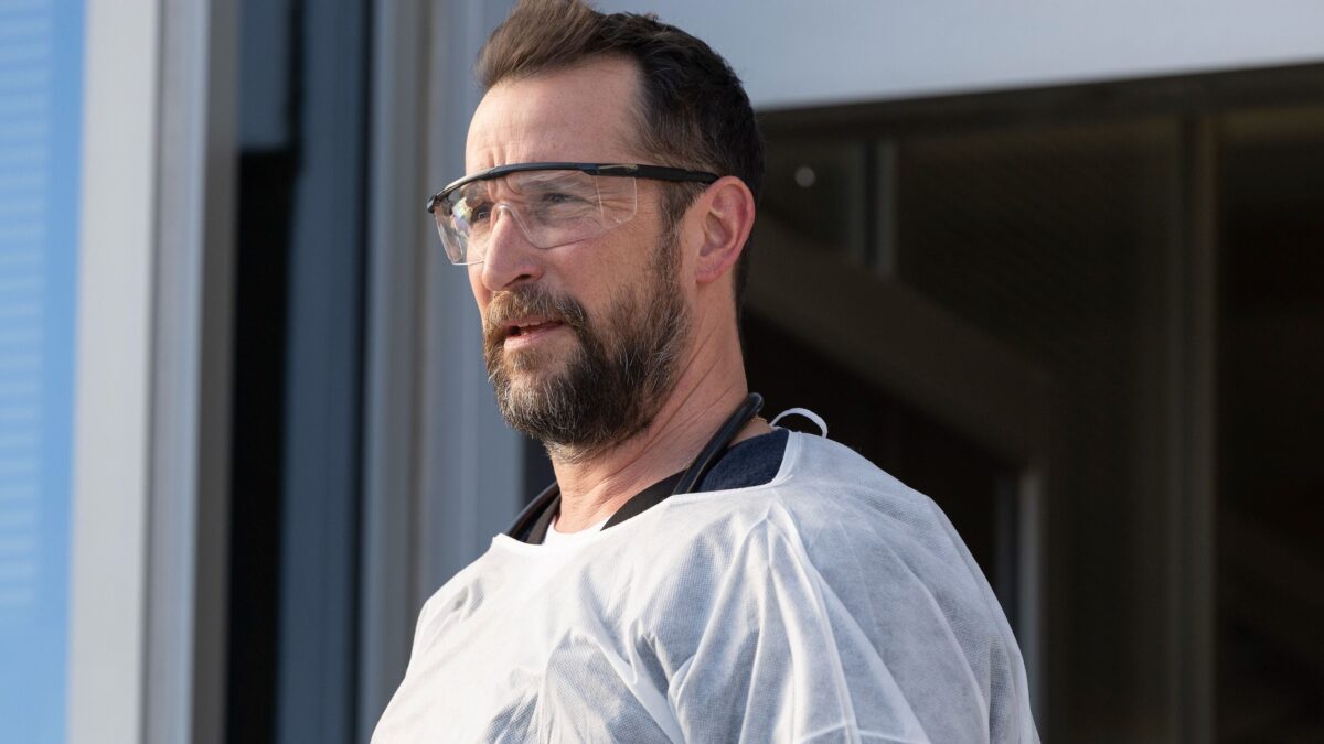 Noah Wyle as Dr. Robby in protective gear in The Pitt emergency room
