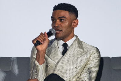 Owen Thiele in a cream polka-dot double-breasted suit speaking into a microphone on a panel at the Newport Beach TV Fest, June 2026