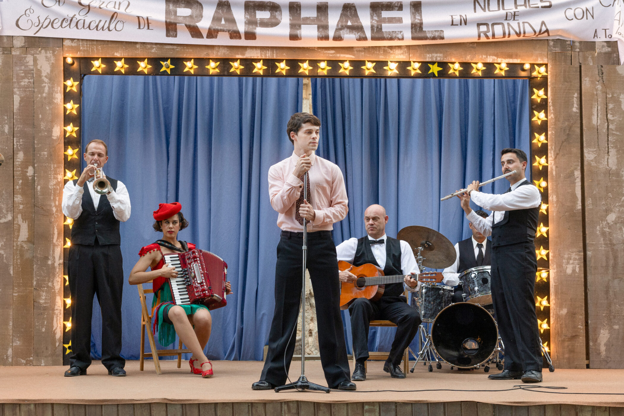 Raphael performing with a band on a village stage