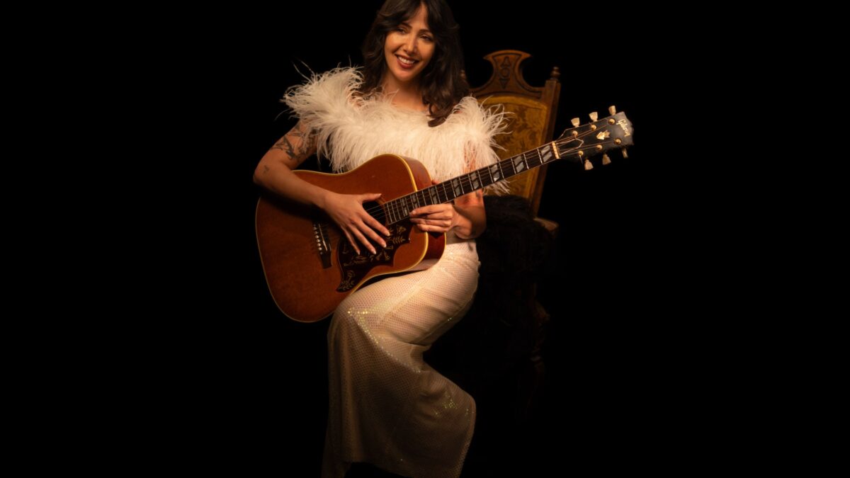 Biita Houdei seated with an acoustic guitar