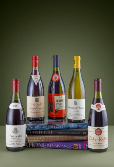 Wine bottles from the Dr. Remington Norman cellar resting on his books including The Great Domaines of Burgundy and Grand Cru