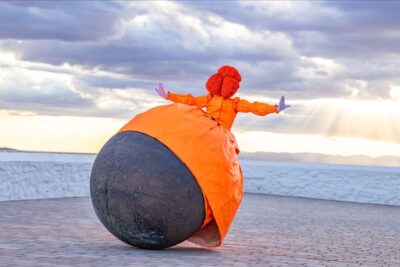 Performer in orange tentetieso costume outdoors, Menina by 7 Bubbles at Coslada Radial