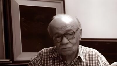 Ernesto Sabato seated with a book in his studio