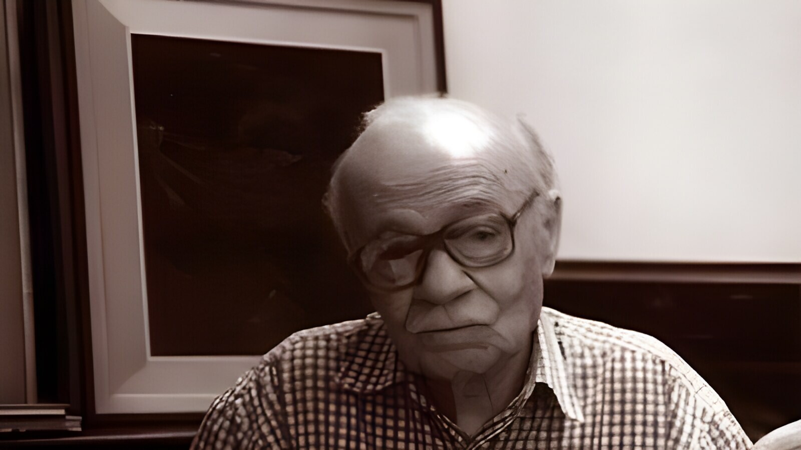 Ernesto Sabato seated with a book in his studio