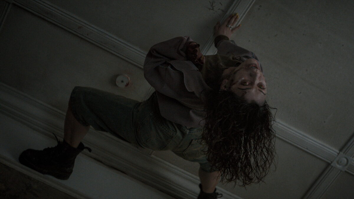 A possessed family member crawling across a ceiling in a scene from Evil Dead Burn