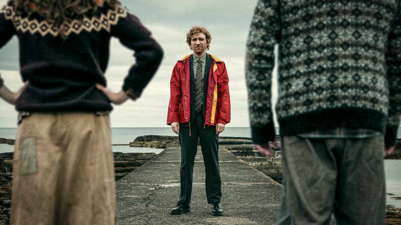 Domhnall Gleeson as Daniel faces two islanders on a stone jetty in Louis Paxton's The Incomer.