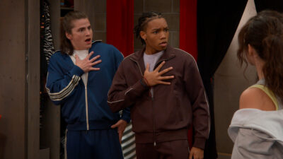 Two students in tracksuits react in a corridor at Hollywood Arts