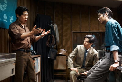 Still from Hur Jin-ho's The Assassin(s): the detective and two reporters confer in a 1970s Seoul broadcast station.