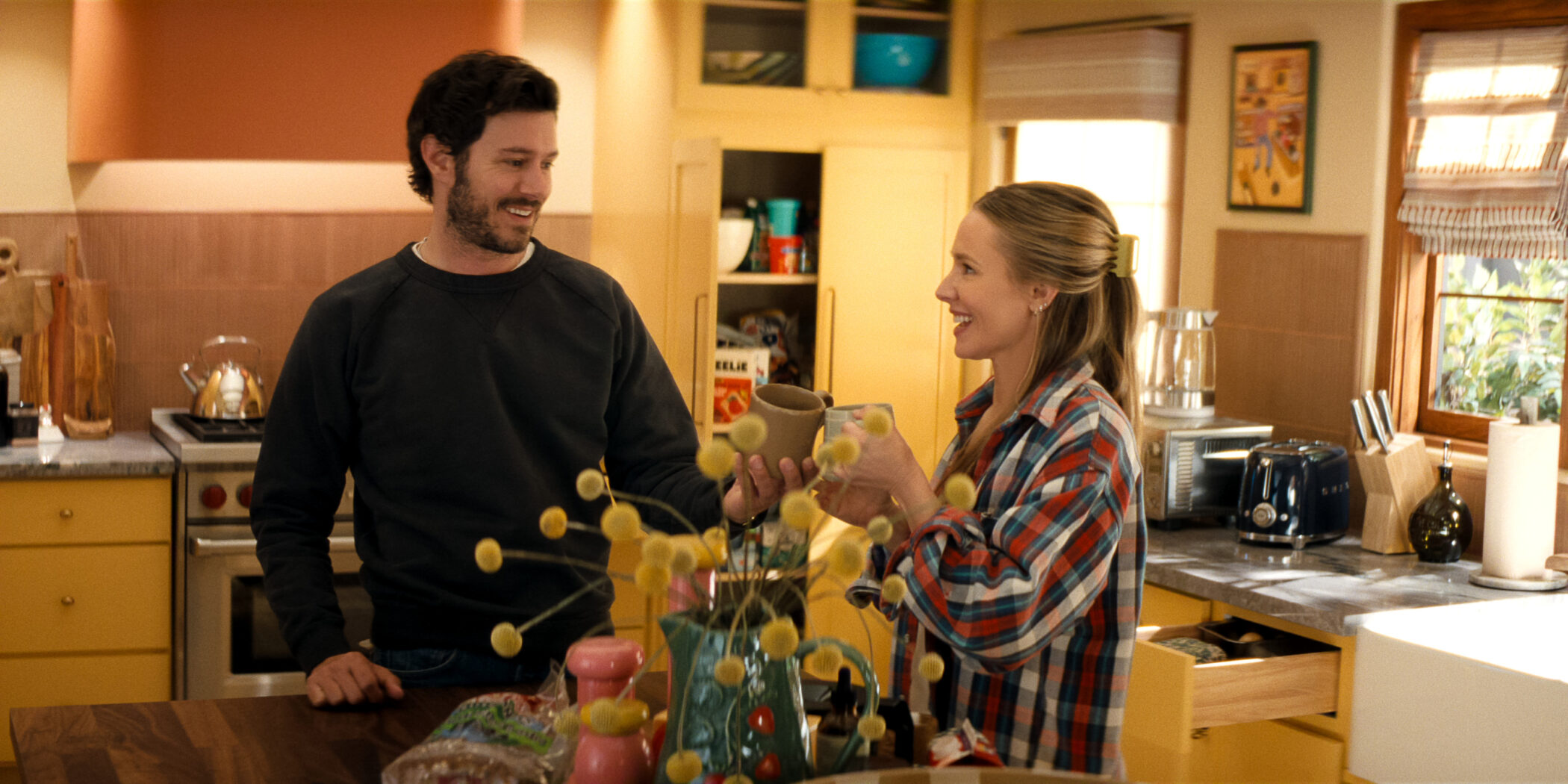 Adam Brody y Kristen Bell brindan con dos tazas en la cocina en Nobody Wants This