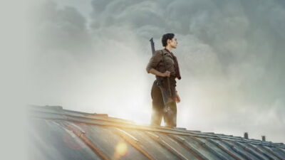 A Resistance fighter stands against smoke on a rooftop in Antonin Baudry's De Gaulle: Liberté.