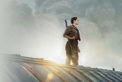 A Resistance fighter stands against smoke on a rooftop in Antonin Baudry's De Gaulle: Liberté.
