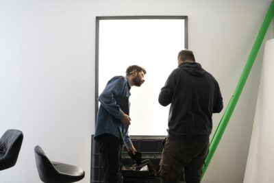 Two crew members setting up a light panel on a production set