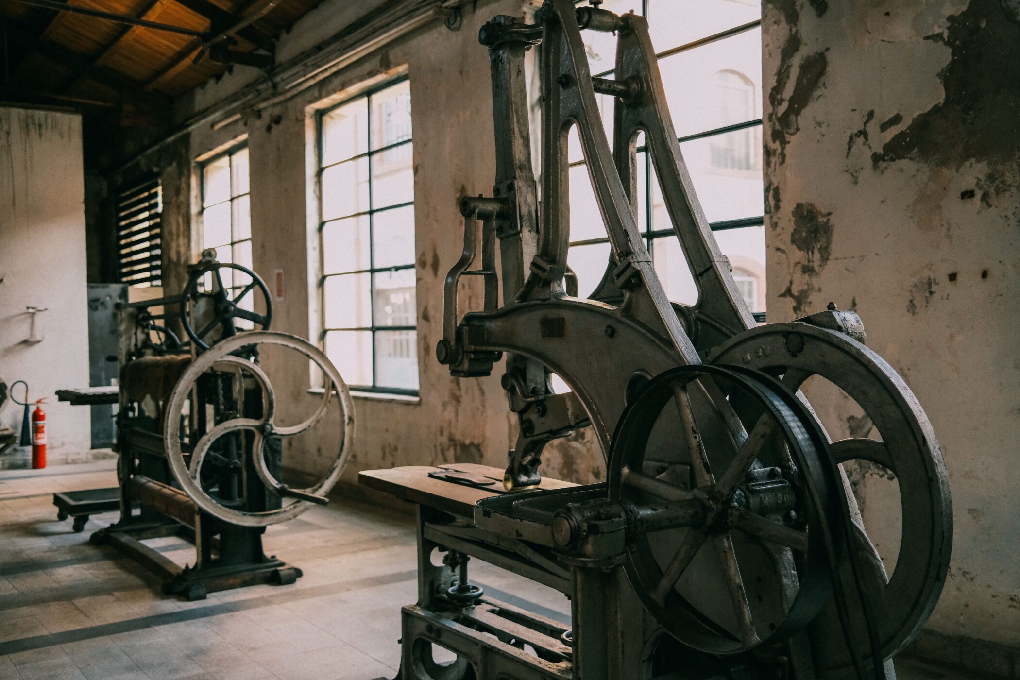 Vintage industrial machinery inside a weathered factory building, depicting early mechanized production from the Industrial Revolution era