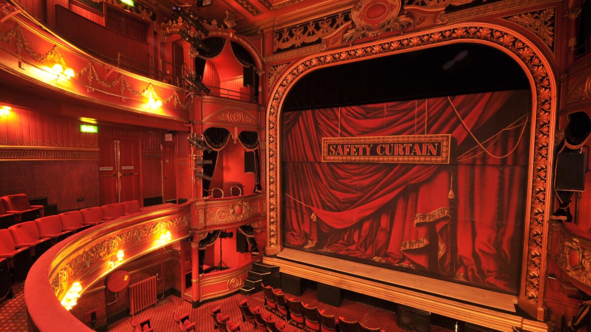 The ornate Victorian interior of Theatre Royal Stratford East, with gilded balconies and red safety curtain