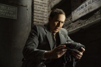 Nicolas Cage examining a folded cloth in a dark alley in Spider-Noir