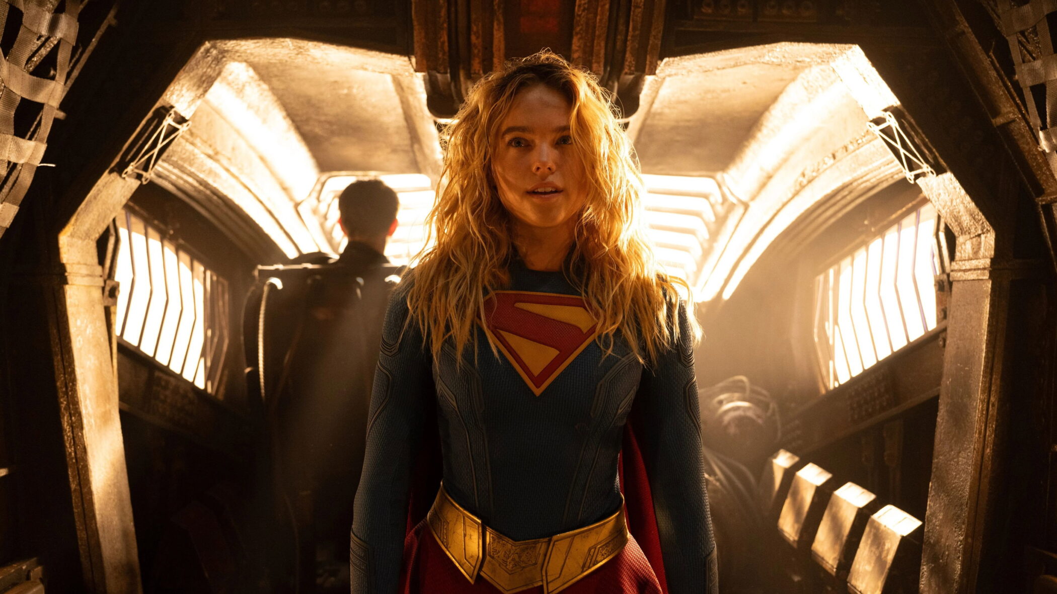 Milly Alcock as Supergirl standing in a dramatically lit corridor in DC Studios film