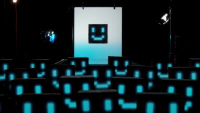 Una sala de cine llena de figuras con cara de pixel frente a una pantalla, en el documental The AI Doc: Or How I Became an Apocaloptimist